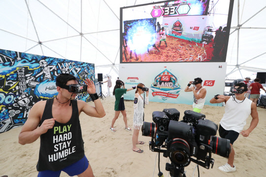 13일 KT가 부산 해운대 해수욕장에서 개최한 5G 체험 행사 '5G 랜드'에서 모델들이 혼합현실(MR) 스포츠 '하도(HADO)'를 소개하며 시연하고 있다.  KT 제공